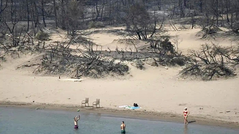 Fotografia dimineții - Turiști pe o plajă din Rodos afectată de incendiile din ultimele zile