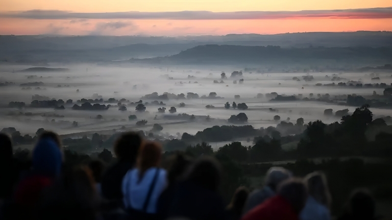 Fotografia dimineții - Mai multe persoane așteaptă răsăritul soarelui în ziua solstițiului de vară, la Glastonbury Tor. În fiecare an, oamenii se adună la fața locului, considerat de unii a fi Avalonul legendei arthuriene…